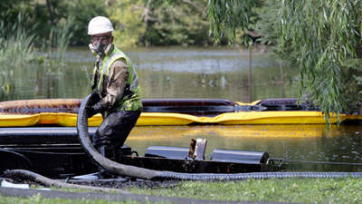 A worker from Enbridge skims oil off the surface of the Kalamazoo River after a pipeline ruptured in Marshall, Michigan. (July 27, 2010) - photo Andre J. Jackson/MCT