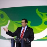 Conservative MP James Moore poses in front of an artist's depiction of a wild BC salmon; last week, Moore abandoned the real thing.